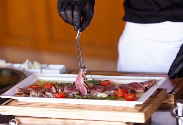 De chef bereidt een steak in de hal van het restaurant