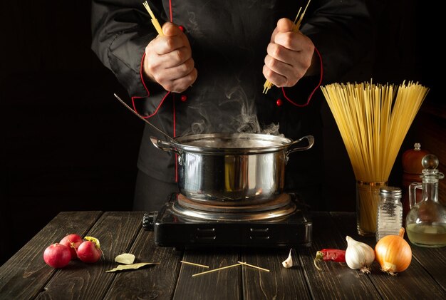 De chef bereidt Italiaanse pasta De kok bewaart spaghetti in de keuken Europese keuken