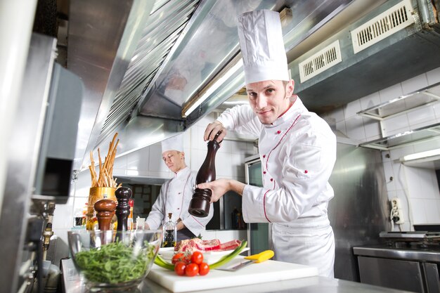 De chef-kok bereidt een gerecht in de keuken van restoran.