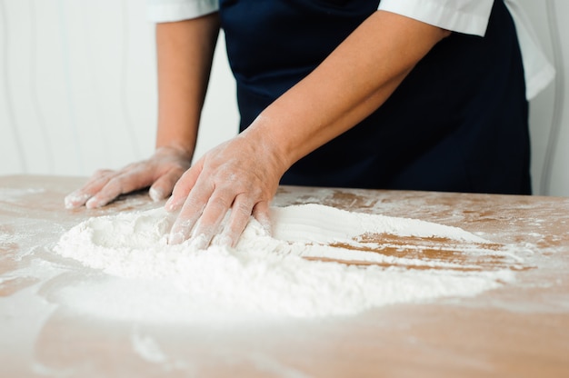 De chef-kok bereidt het deeg - het proces van het maken van deeg in de keuken