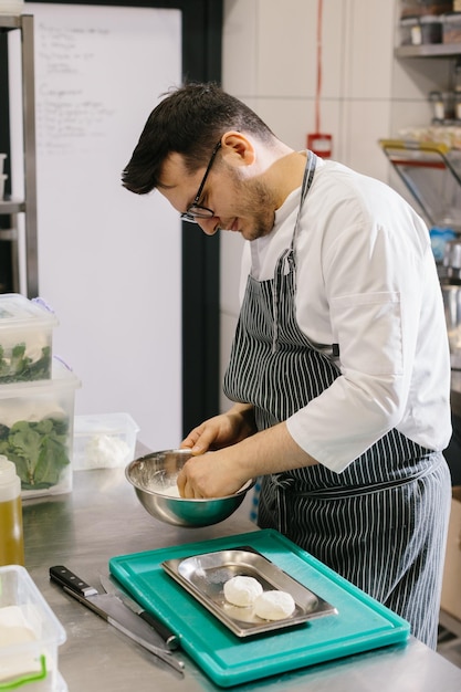 De chef-kok bereidt kaaspannenkoeken in de keuken van het café