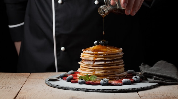 De chef-kok bereidt pannenkoeken met bessen.