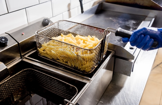 De chef-kok die frieten kookt