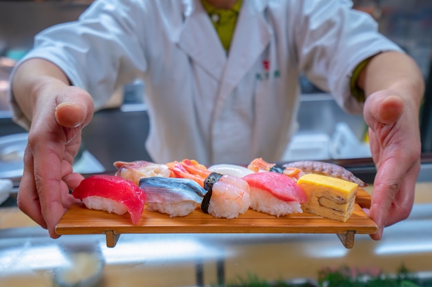 De chef-kok diende Japanse Sushi met de hand op beboste plaat