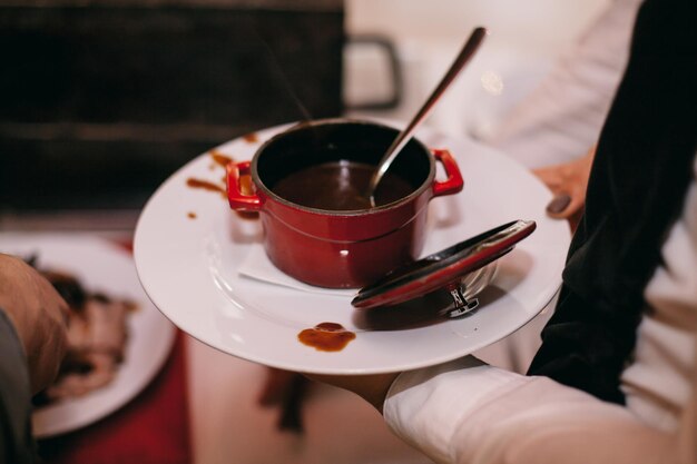 De chef-kok giet roomsoep in een bord, bovenaanzicht. De kok in het restaurant schenkt roomsoep in