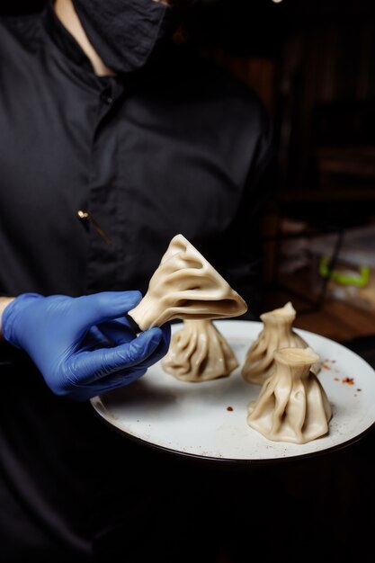 De chef-kok houdt een khinkali-knoedel van het bord