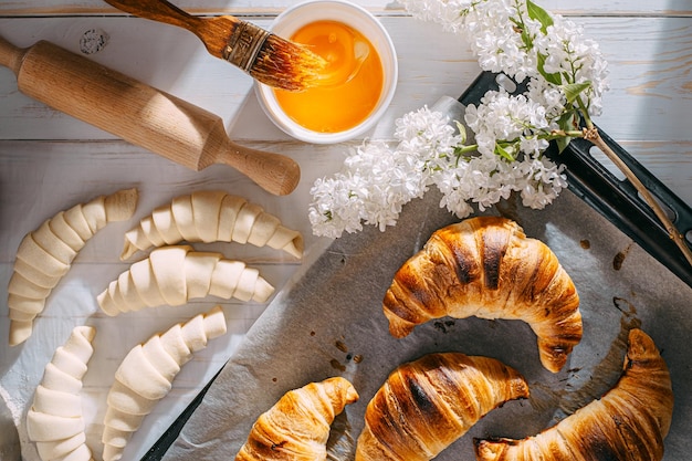 De chef-kok kookt 's ochtends croissants in de keuken op tafel kant-en-klare en rauwe croissants en dezelfde ingrediënten voor hun bereiding