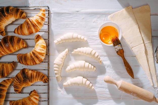 De chef-kok kookt 's ochtends croissants in de keuken op tafel kant-en-klare en rauwe croissants en dezelfde ingrediënten voor hun bereiding