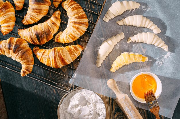 De chef-kok kookt 's ochtends croissants in de keuken op tafel kant-en-klare en rauwe croissants en dezelfde ingrediënten voor hun bereiding