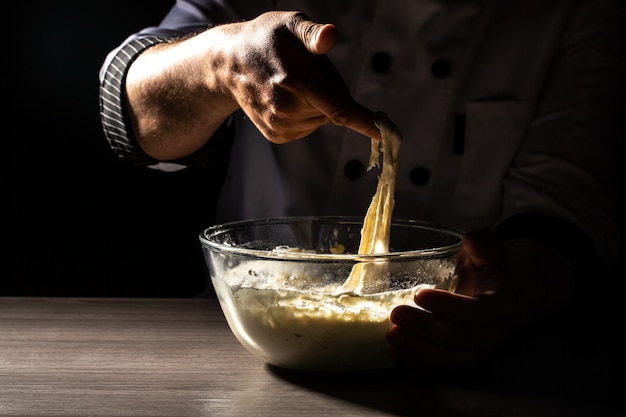 De chef-kok overhandigt kokend deeg op donkere houten achtergrond