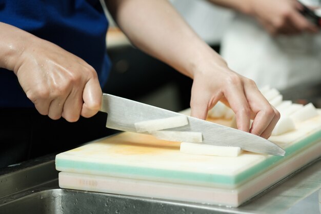 De chef-kok sneed groente op scherpe raad met mes Japan