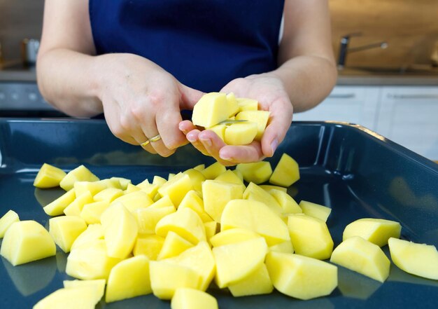 De chef-kok sneed groenten in een bakplaat tijdens het maken van ovengeroosterde groenten