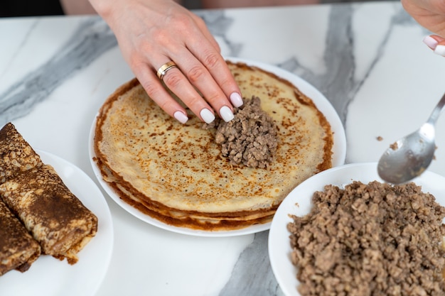 De chef-kok stopt de pannenkoeken met gehakt