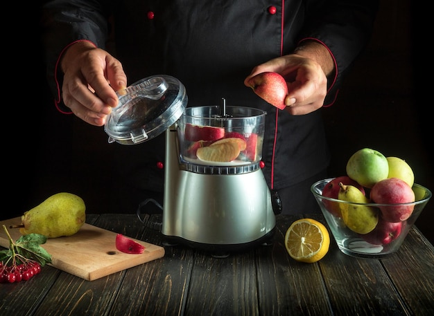 De chef-kok voegt een gesneden appel toe aan de blender voor een zoete fruitdrank Gezond Vegetarisch Ontbijt of Diner Idee