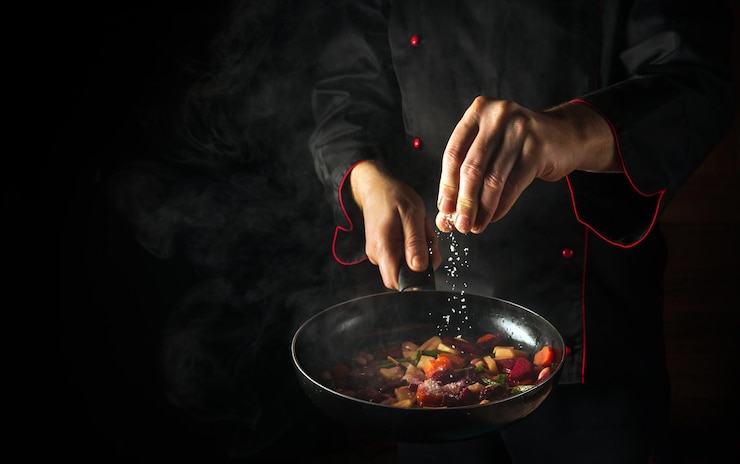 Foto de chef voegt zout toe aan een dampend hete pan