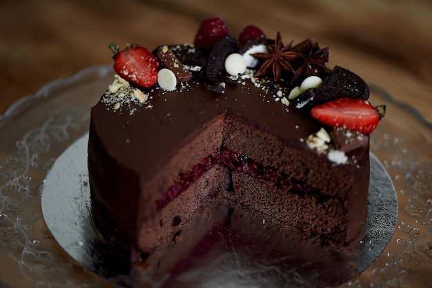 De chocolade-kersentaart gedecoreerd met aardbeienkoekjes en aardbeientaart Een meesterwerk van culinaire kunst