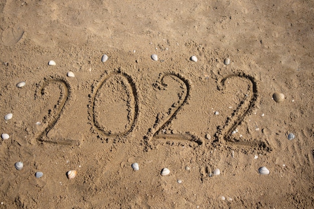 De cijfers 2022 zijn met de hand geschreven op het zand aan de kust rond de schelp