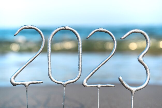 Foto de cijfers voor het komende nieuwe jaar 2023 temidden van golven op het strand. nieuwjaarsviering concept in exotisch land. detailopname