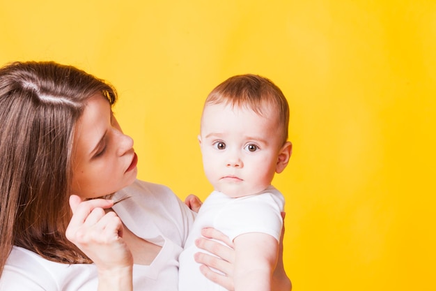 De close-up van een moeder en een baby in witte kleding op een oranje achtergrond