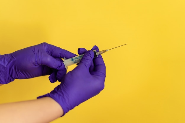 De close-up van verpleegster dient handschoenen in voorbereidend een spuit voor injectie