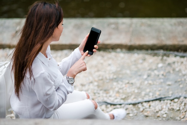 De close-up van vrouwelijke handen houdt cellphone in openlucht op de straat. Man met behulp van mobiele smartphone.