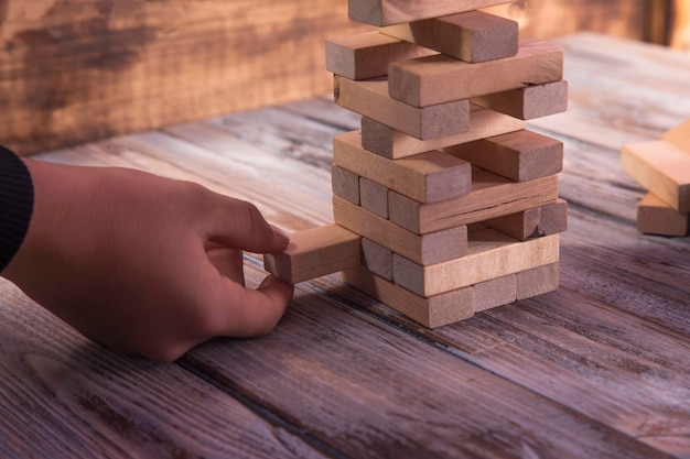 De close-uphand neemt één blok op een houten bloktoren