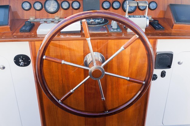 Foto de cockpit van een luxe jacht met een klassiek rond stuurwiel en navigatieapparatuur