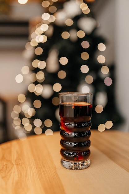 De cocktail van glühwein op tafel met de bokeh van de kerstboom