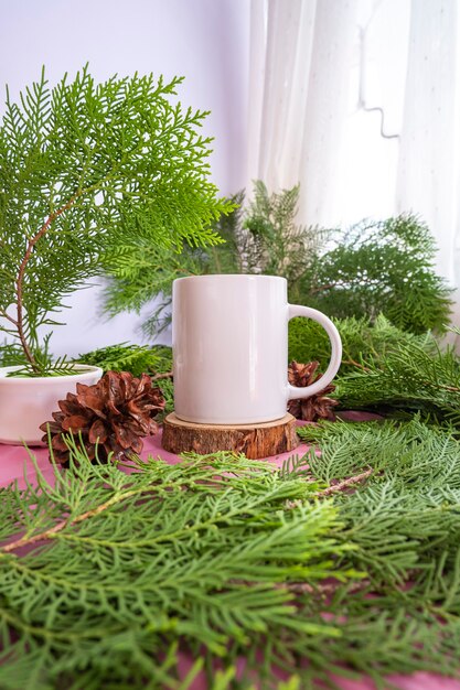 De compositie geeft het product weer. witte mok op oud rond hout met decoratie van dennenbladeren. ideeën voor het weergeven van zomerproducten