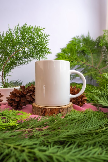 De compositie geeft het product weer. witte mok op oud rond hout met decoratie van dennenbladeren. ideeën voor het weergeven van zomerproducten