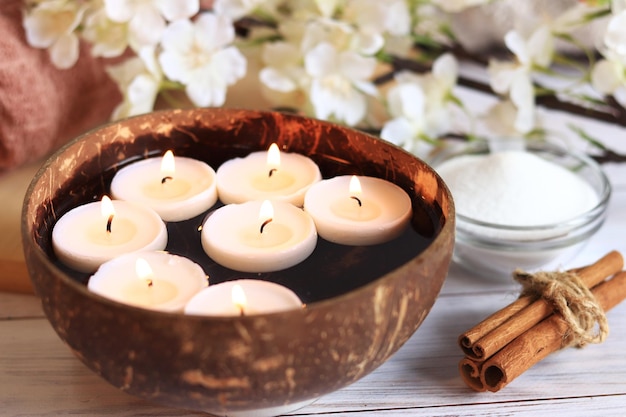 De compositie voor spa met brandende kaarsen in het water Kokoskom met kaarsen