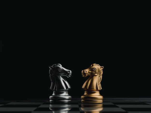 De confrontatie tussen gouden en zilveren paarden, ridderschaakstuk dat samen op een schaakbord staat op een donkere achtergrond. Leiderschap, partnerschap, concurrent, concurrentie en bedrijfsstrategie concept.