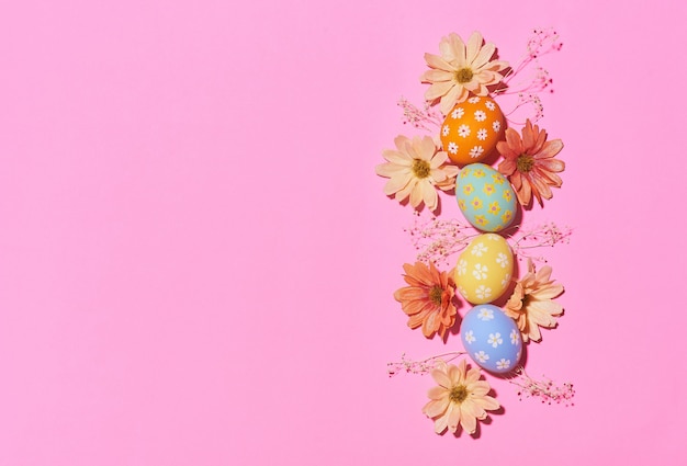 De creatieve Pasen-eieren van de vakantielay-out kleurden met de hand gemaakte verf met bloem op roze achtergrond. Seizoengebonden vlak leg concept.
