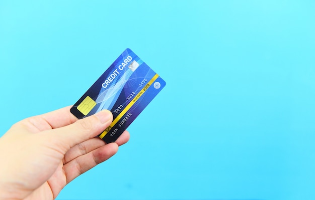 De creditcard van de handholding op blauwe achtergrond - betaling het online winkelen die met het concept van de creditcardtechnologie e portefeuille betalen