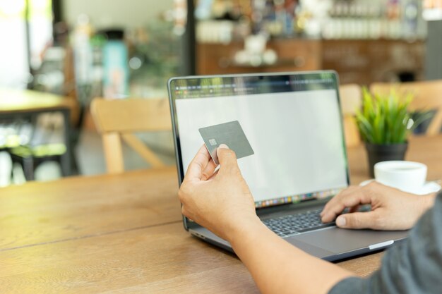 De creditcard van de zakenman online werkende handholding en het gebruiken van laptop in koffie.