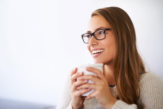 De dag ontspannen met een lekker kopje koffie Shot van een jonge vrouw die thuis koffie drinkt