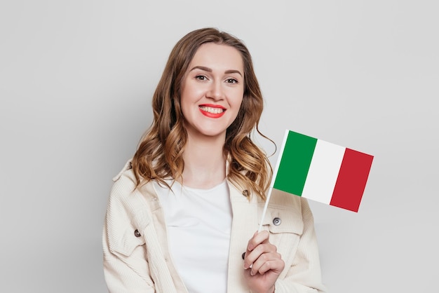 De dag van de republiek van Italië Gelukkige jonge vrouw die de kleine vlag van Italië houdt die op grijze achtergrond in studio wordt geïsoleerd