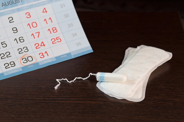 De dagelijkse vrouwelijke pad en tampon op de kalender, waarin de dag van het begin van de menstruatiecyclus wordt gemarkeerd