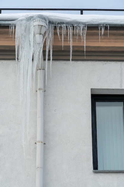 De daken van de gebouwen zijn bedekt met sneeuw en ijs na een grote sneeuwval Enorme ijspegels hangen aan de gevels van gebouwen De val van ijspegels vormt een gevaar voor het leven van mensen