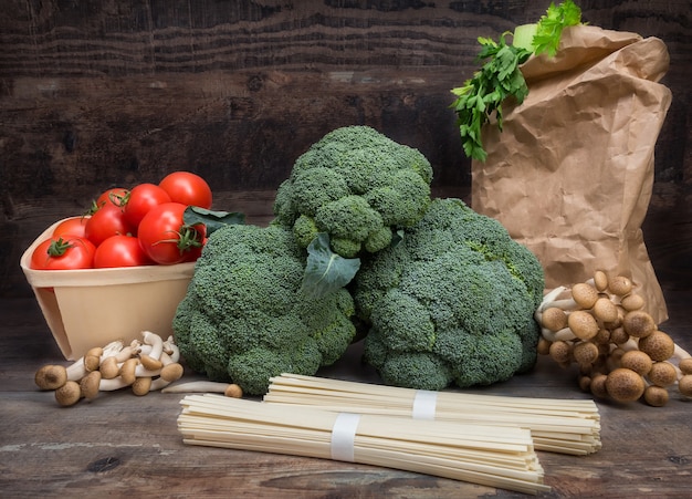 De de koolbroccoli van stillevengroenten met tomaten schiet houten spaghetti groene bladeren als paddestoelen uit de grond
