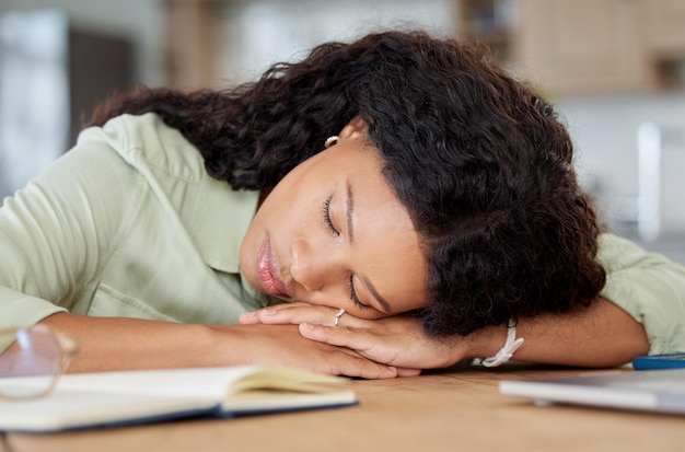 De deadlines kunnen wachten. Shot van een jonge vrouw die aan een tafel slaapt terwijl ze thuis werkt.