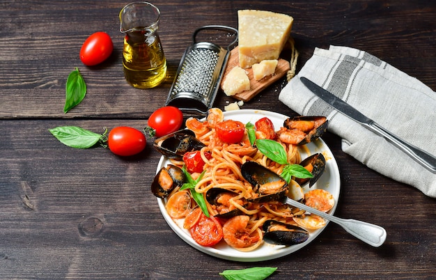 De deegwaren van spaghettizeevruchten met tweekleppige schelpdieren en garnalen met mosselen en tomaten in een witte plaat met op een houten lijst. recept uit de italiaanse keuken. bovenaanzicht