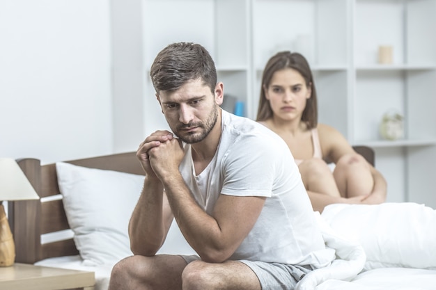 De depressieve man zit naast de vrouw in bed