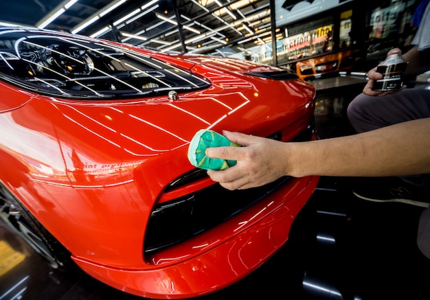 De dienstarbeider die van de auto nanodeklaag op een autodetail toepast