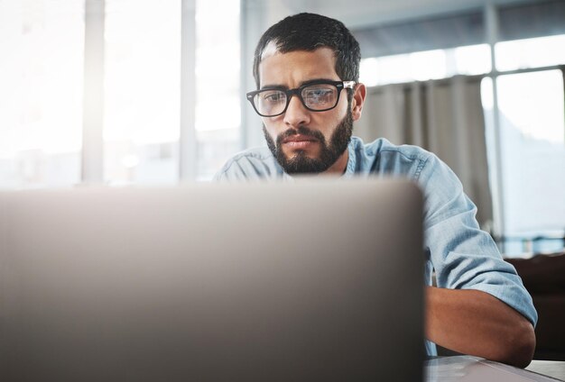 De digitale werker krijgt dingen altijd voor elkaar Foto van een jonge man die zijn laptop gebruikt terwijl hij thuis werkt