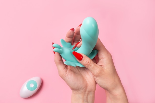 De Dildo in de hand op een roze muur, seksspeeltje