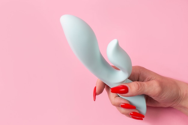 Foto de dildo in de hand op een roze muur, seksspeeltje