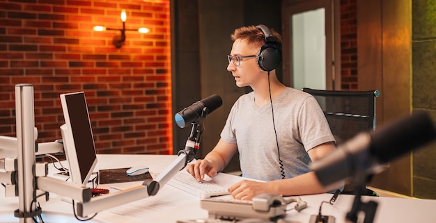 De DJ host het programma en communiceert met het publiek in de uitzending van het radiostation. De omroeper leest het nieuws. Een mannelijke radiopresentator spreekt in een microfoon en neemt een podcast op