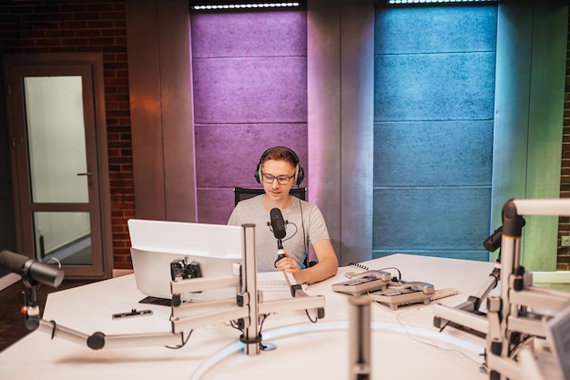 De DJ presenteert het programma en communiceert met het publiek in de uitzending van het radiostation De omroeper leest het nieuws Een mannelijke radiopresentator spreekt in een microfoon en neemt een podcast op