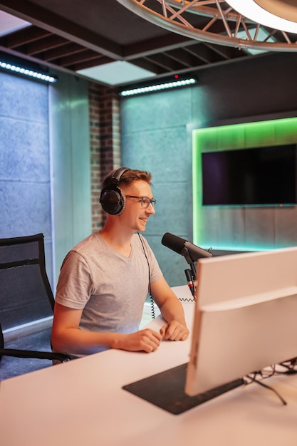 De DJ presenteert het programma en communiceert met het publiek in de uitzending van het radiostation De omroeper leest het nieuws Een mannelijke radiopresentator spreekt in een microfoon en neemt een podcast op